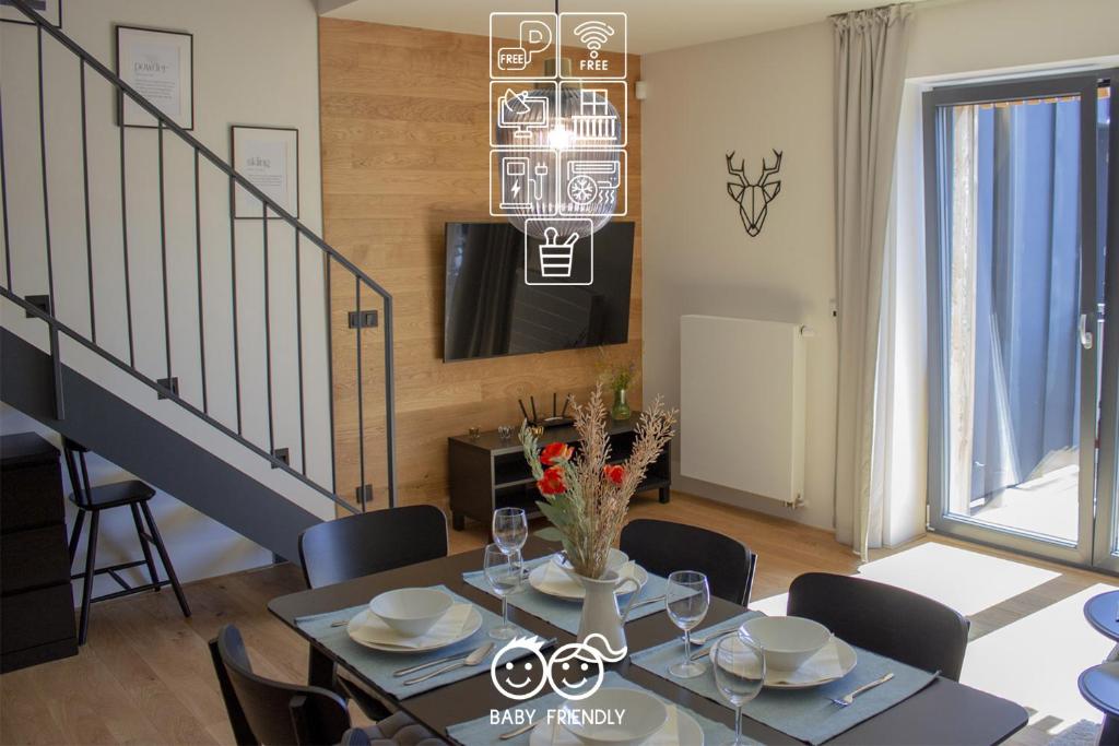 uma sala de jantar com uma mesa com cadeiras e uma televisão em ENJOYHARRACHOV - Atraktivní slunný klimatizovaný apartmán 14 v centru Harrachova se saunou, parkováním, Wifi-WLAN, SAT, herní konzolí, PC s win 10, Netflix zdarma a možností dobíjení auta s jedinečným výhledem na Čertovu horu se skokanskými můstky em Harrachov