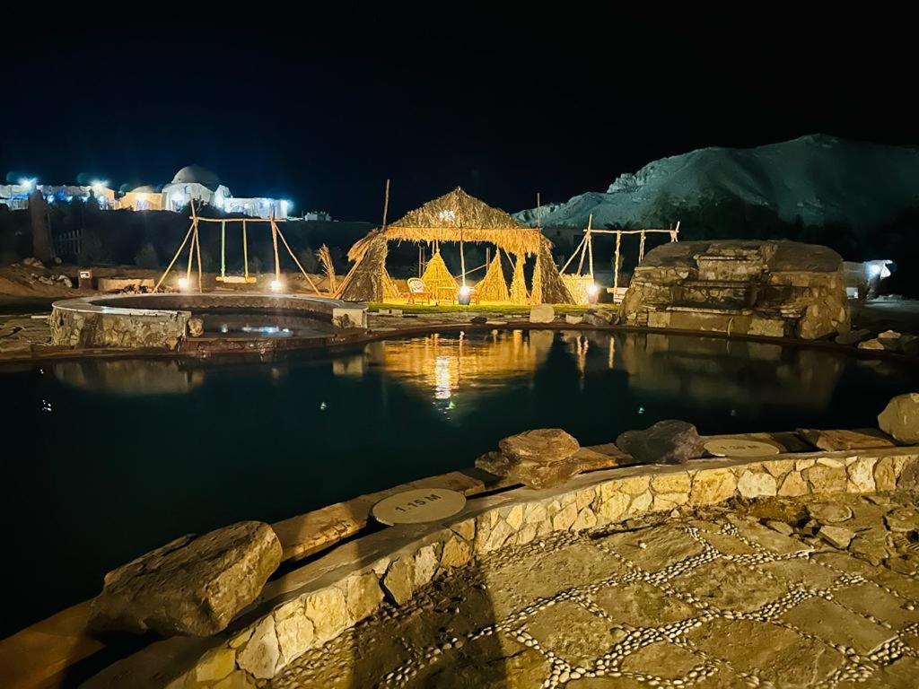 a large pool of water at night with lights at Qasr El Bagawat Hotel in ‘Ezbet Halfa