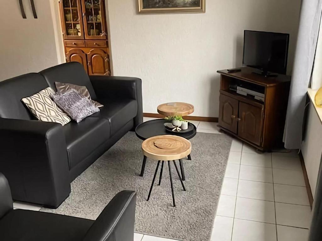 a living room with a black couch and a tv at Tranquil Holiday Home in Margraten in Margraten