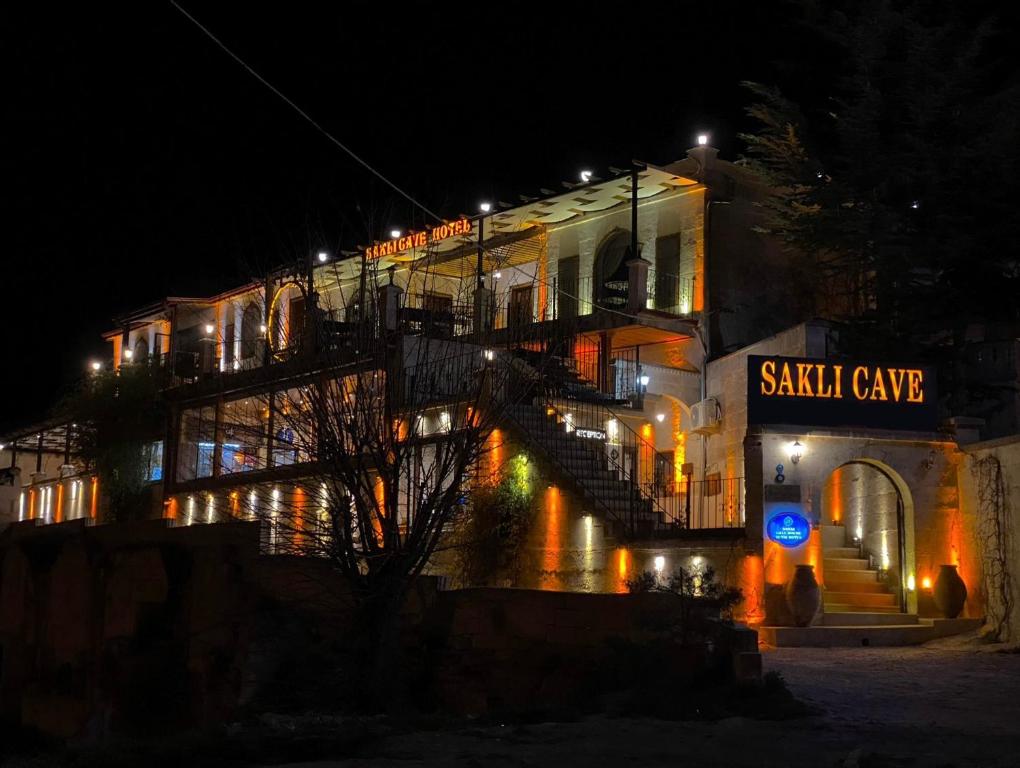 a large building with a sasha cure sign on it at night at Sakli Cave House in Avanos