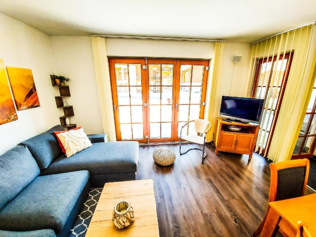 ein Wohnzimmer mit einem blauen Sofa und einem TV in der Unterkunft Ferienwohnung für 4 Personen ca 55 m in Rauris, Salzburger Land Rauristal in Rauris