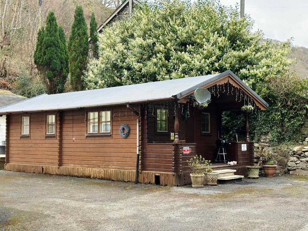 eine kleine Holzhütte mit einem Zinndach in der Unterkunft Panteinion Hall- The Cabin in Fairbourne