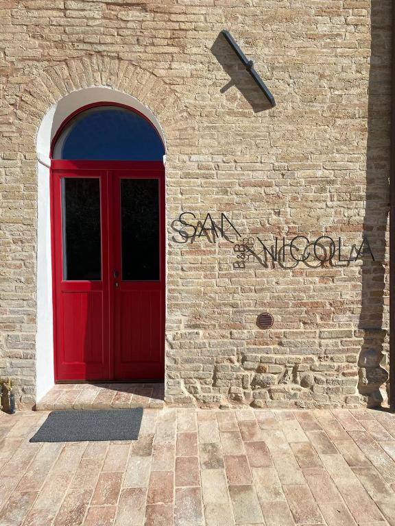 uma porta vermelha do lado de um edifício de tijolos em B&B San Nicola em Porchia