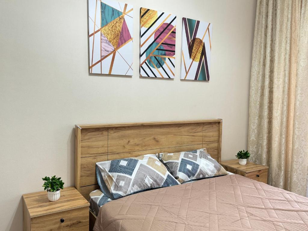 ein Schlafzimmer mit einem Bett mit zwei Gemälden an der Wand in der Unterkunft Dream City in Taldykolʼ