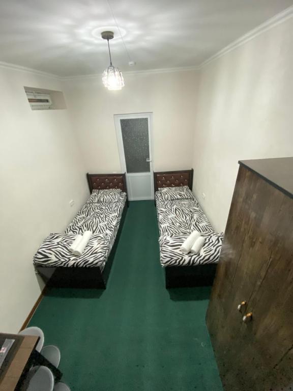 3 camas en una habitación con suelo verde en Family Hotel, en Samarkand