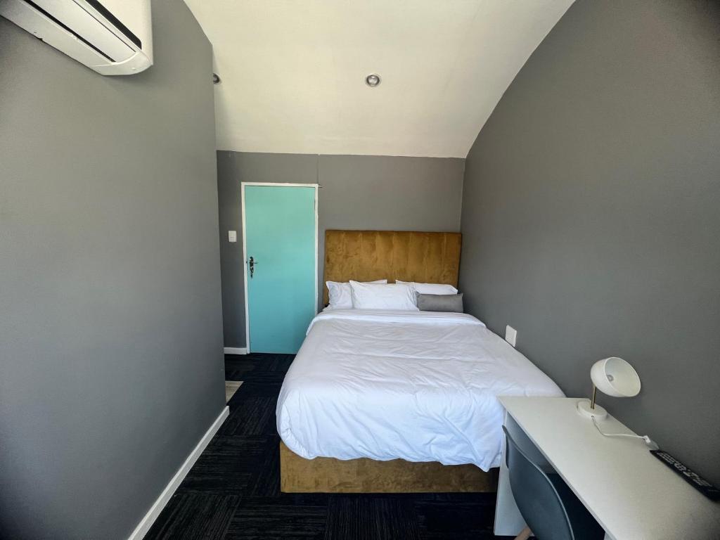 um quarto com uma cama branca e uma secretária em M & B Backpackers em Cidade do Cabo
