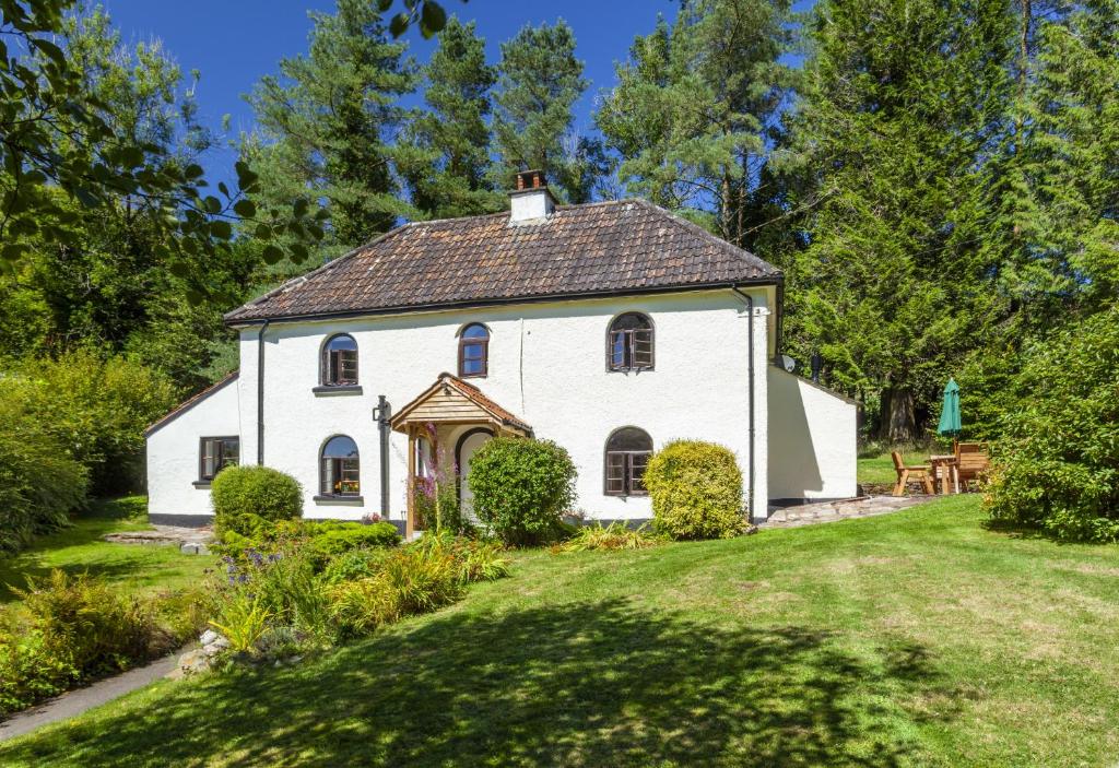 a white house in a yard with trees at Barn Owl Cottage Wheddon Cross in Wheddon Cross
