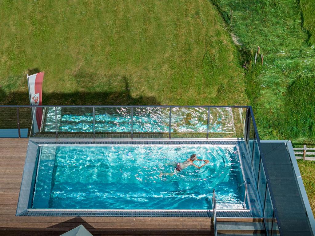 a person swimming in a large swimming pool at Naturhotel Tandler in Sankt Jakob in Defereggen