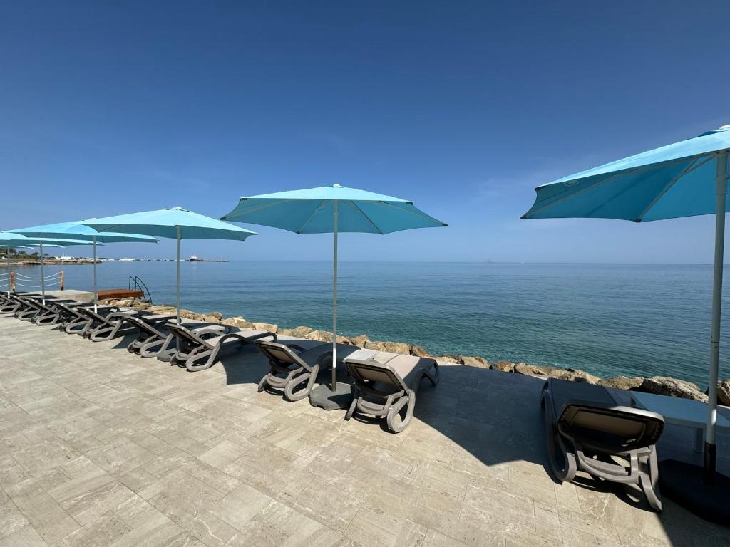 eine Reihe von Stühlen mit Sonnenschirmen am Strand in der Unterkunft High Life in Kyrenia