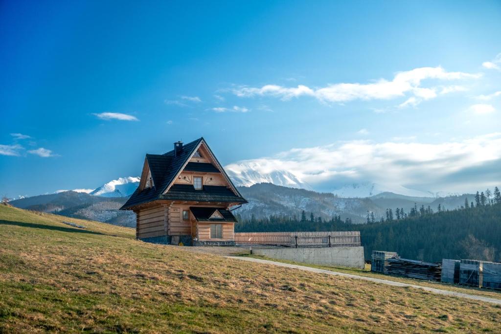 una casa en una colina con montañas al fondo en Domek za Wierchem, en Małe Ciche