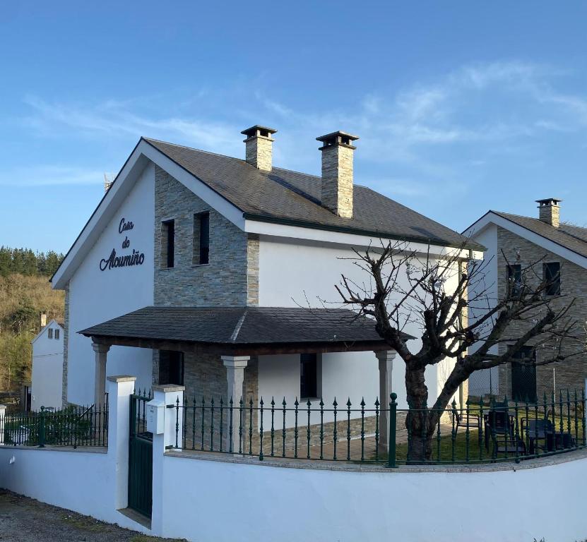 una grande casa bianca con una recinzione di fronte di Casa do Aloumiño a Portomarin