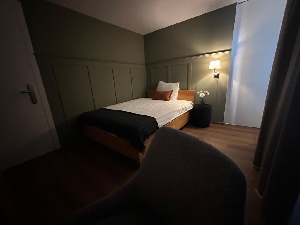 a small bedroom with a bed and a chair at Peterhof Sarnen in Sarnen