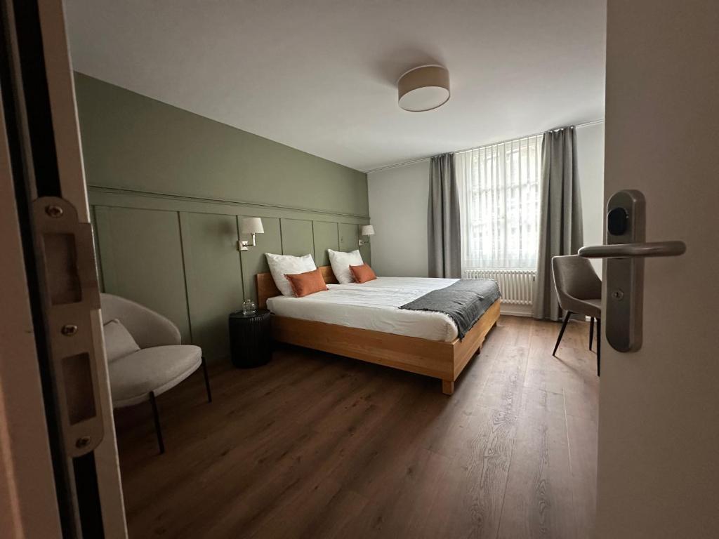 a bedroom with a bed and a chair and a window at Peterhof Sarnen in Sarnen