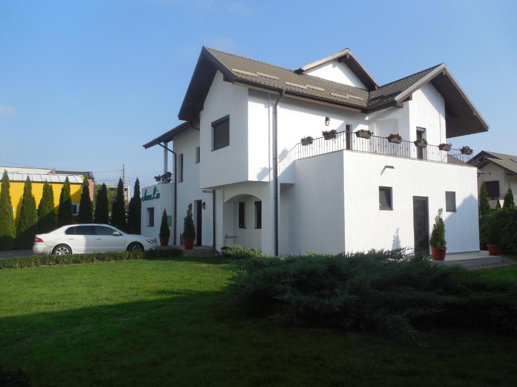 ein weißes Haus mit einem davor geparkt in der Unterkunft Villa AnnaLia - Rooms to Rent in Bacău