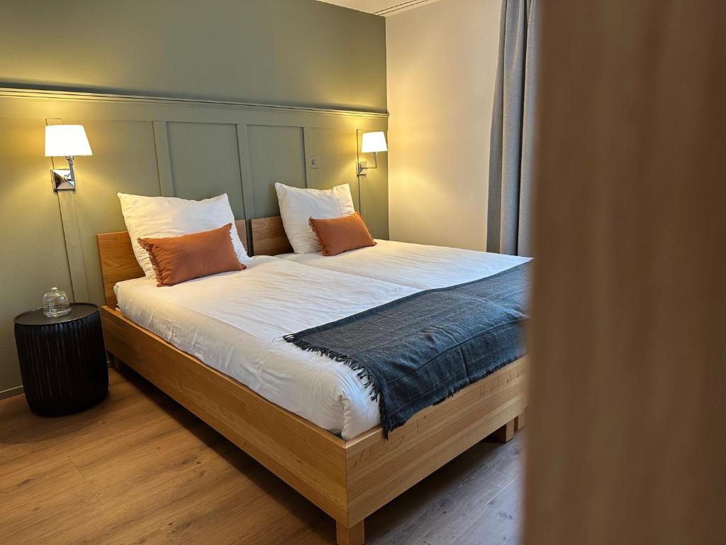 a bedroom with a bed with white sheets and orange pillows at Peterhof Sarnen in Sarnen