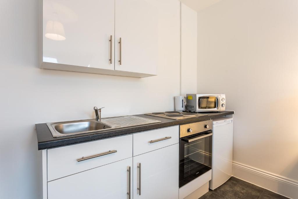 een witte keuken met een wastafel en een magnetron bij West Street Studio Apartments in Southend in Southend-on-Sea