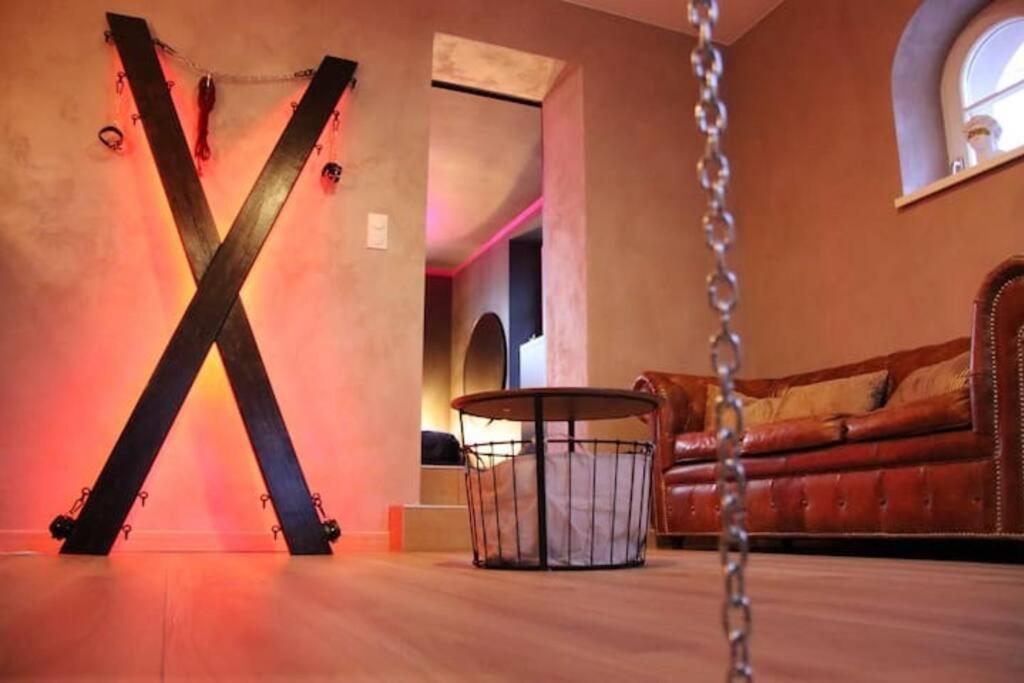 a swing in a room with a couch at Les Secrets du Château - Love Room in Lichtenberg