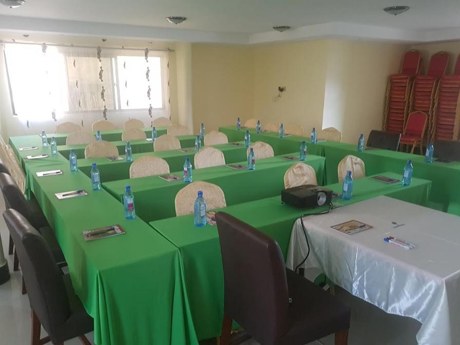 una sala de conferencias con mesas verdes y sillas en The Cannas Hotel Suites, en Kisii
