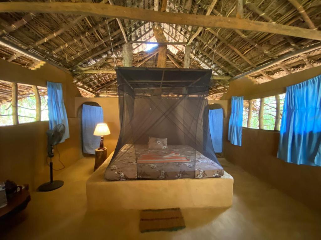 Cama en habitación con cortinas azules en Glimra eco lodge, en Hambegamuwa