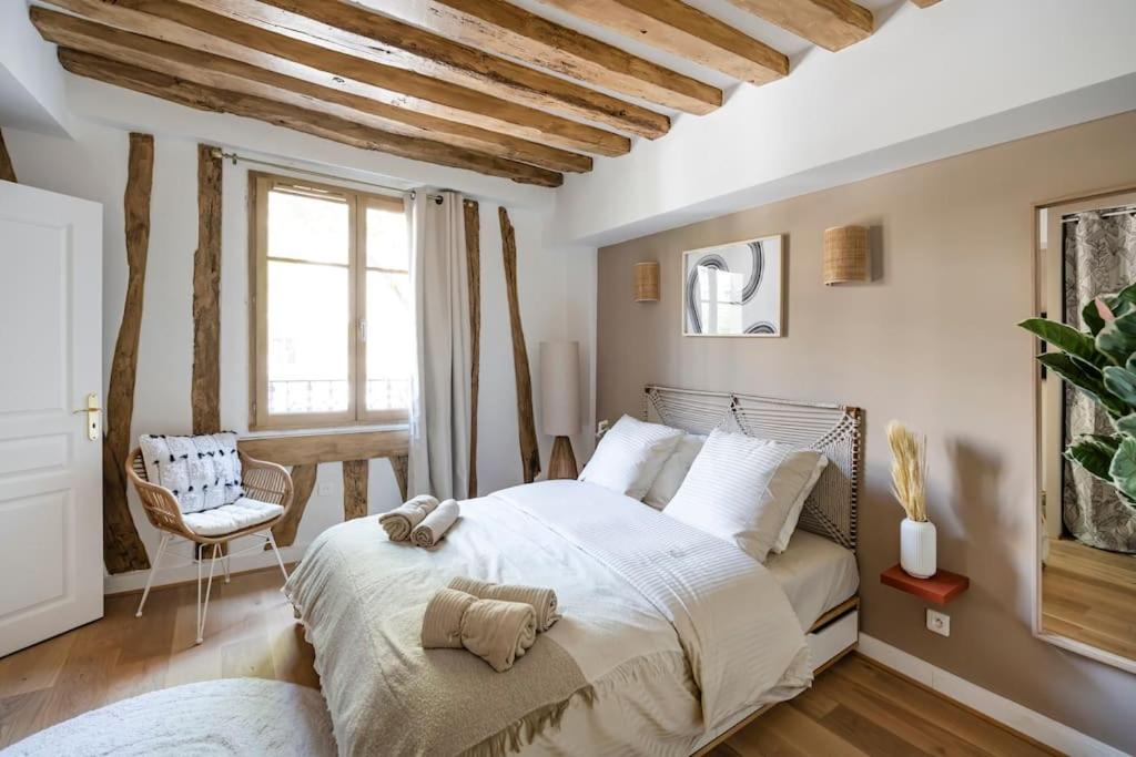 een slaapkamer met een groot wit bed en een stoel bij Pavillon Eden « Le cocon » in Parijs