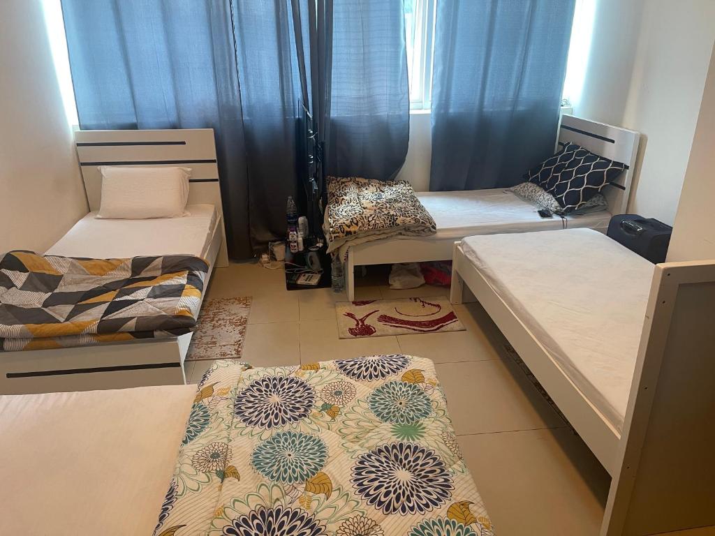 a room with three beds and a rug on the floor at Purity Inn JVC in Dubai