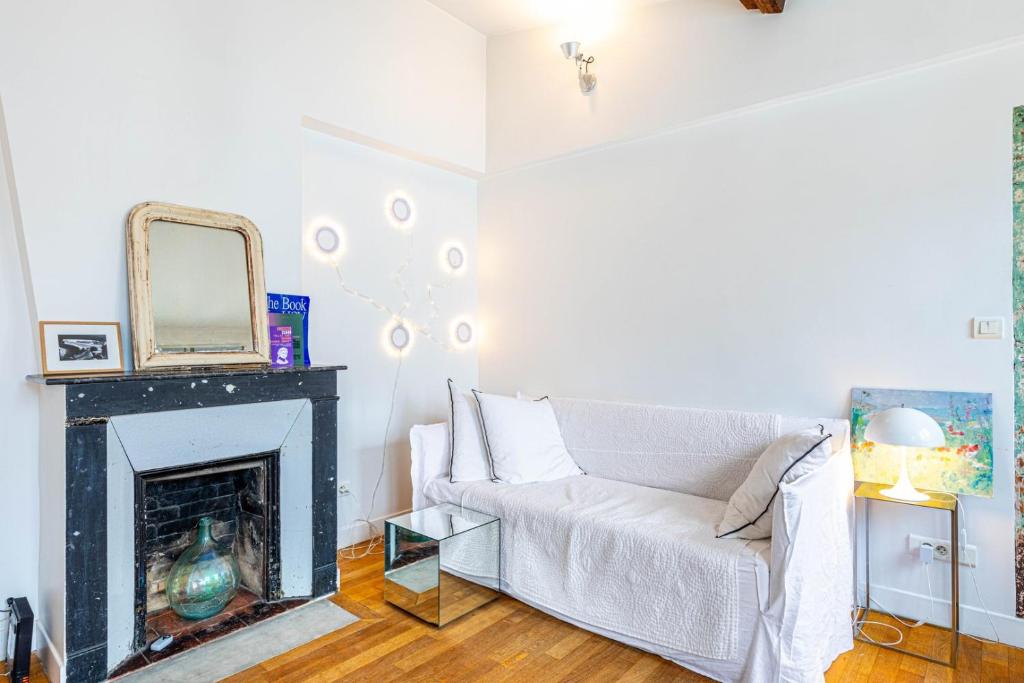 un salon avec un canapé blanc et une cheminée dans l'établissement GuestReady - City center gem near attractions, à Paris