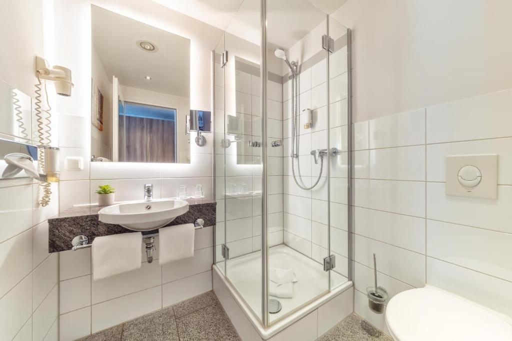 a white bathroom with a sink and a shower at CityClass Hotel am Dom in Cologne