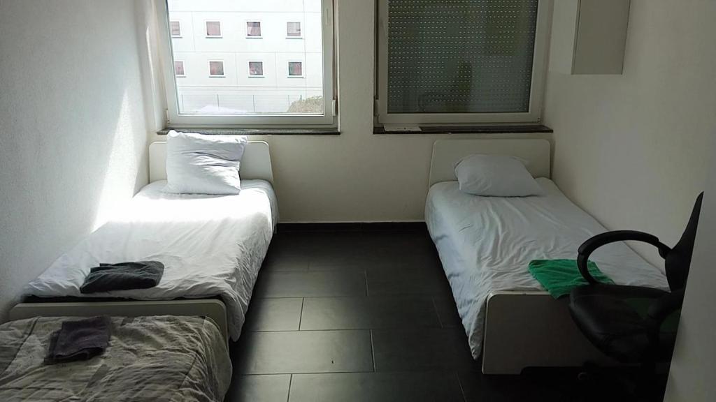 duas camas num pequeno quarto com duas janelas em Viva Zimmer in Heilbronn Zentrum em Heilbronn