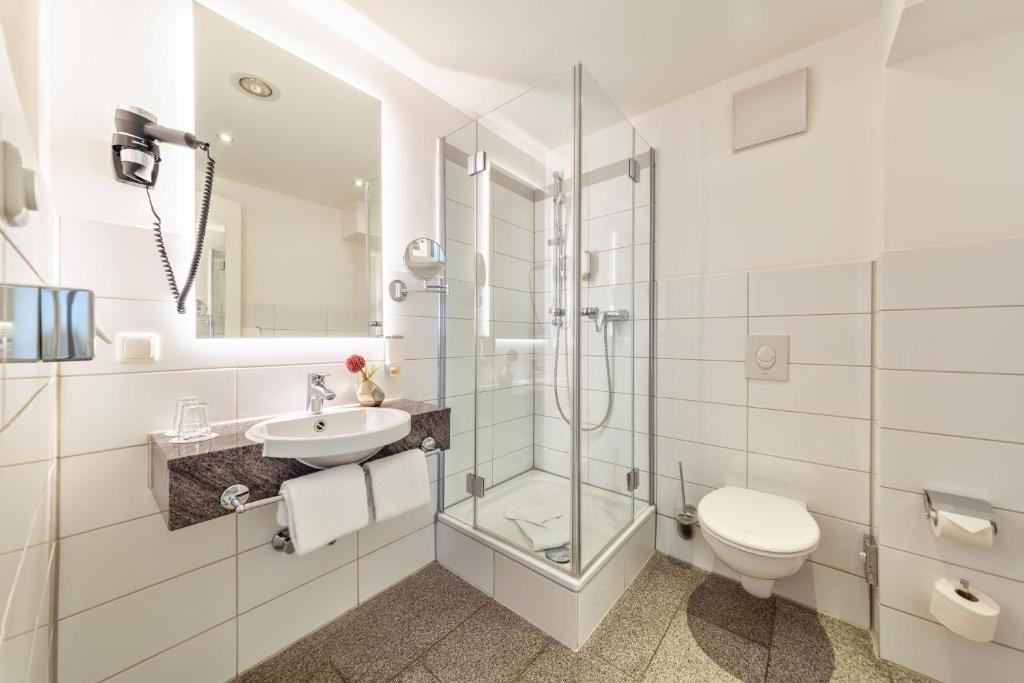 a bathroom with a shower toilet and a sink at CityClass Hotel am Dom in Cologne
