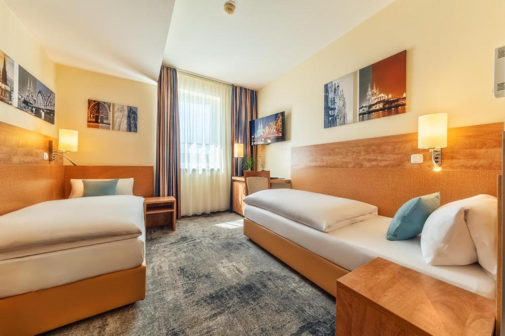 a hotel room with two beds and a desk at CityClass Hotel am Dom in Cologne