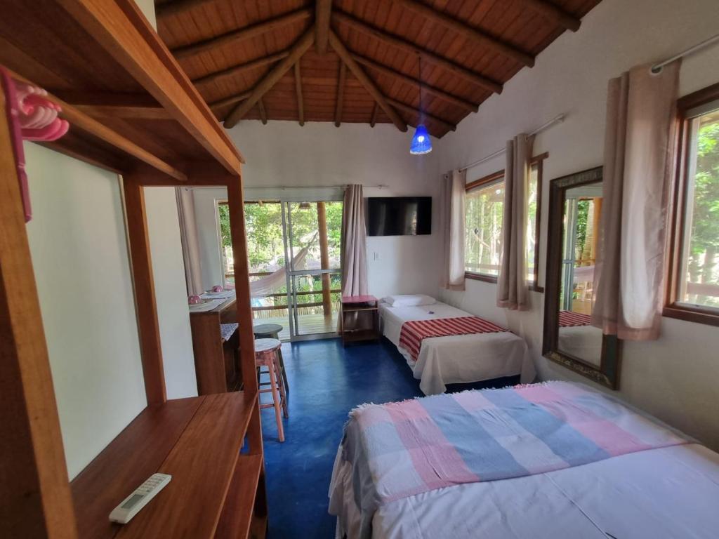1 dormitorio con 2 camas, TV y ventanas en Casa de Sapê, en Arraial d'Ajuda