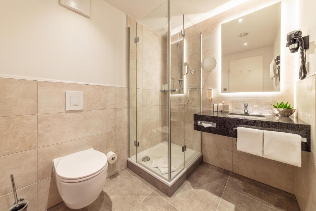 a bathroom with a toilet and a shower and a sink at CityClass Hotel am Dom in Cologne