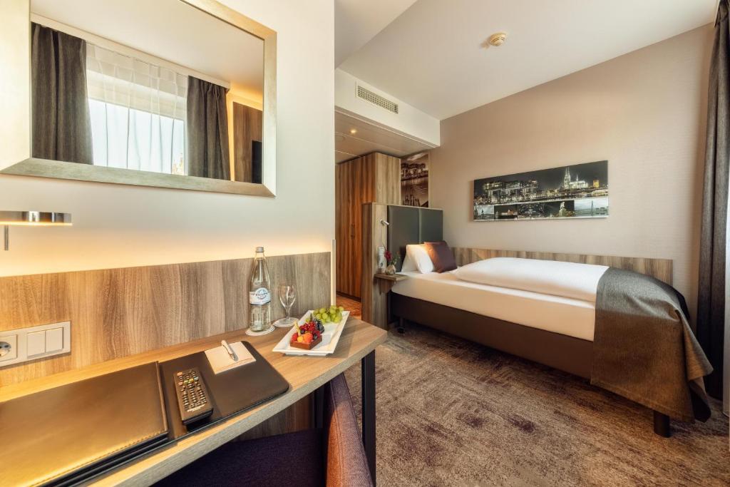 a hotel room with a bed and a desk at CityClass Hotel am Dom in Cologne
