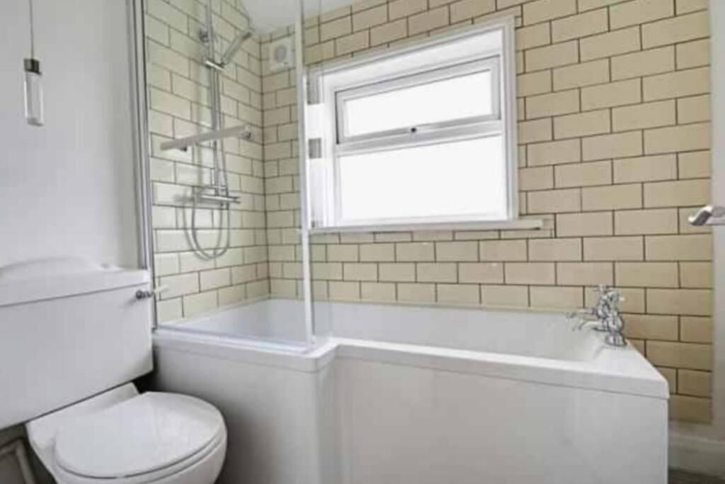 a bathroom with a tub and a toilet and a window at Two bedroom terrace house with parking in Hull