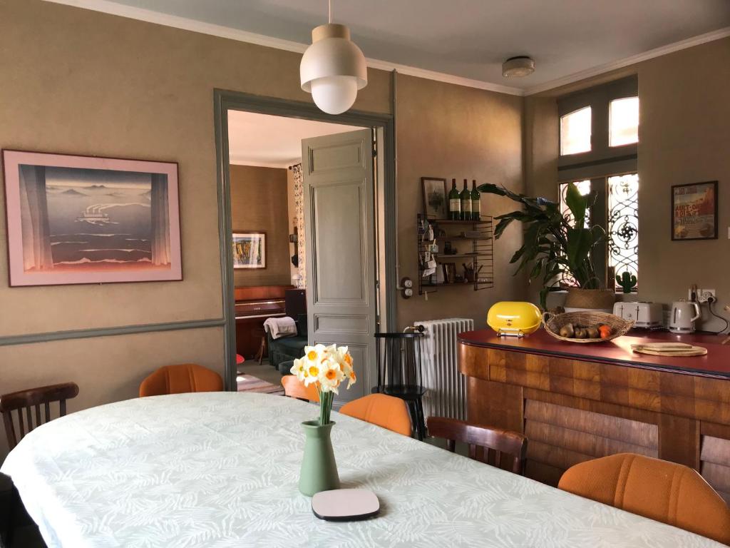 a dining room with a table with a vase of flowers on it at Maison familiale éco rénovée in Ault