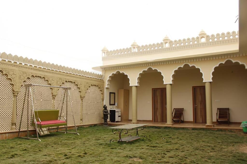 a patio with a swing and a table in a courtyard at Farm Aavjo - A Conscious Stay in Pushkar