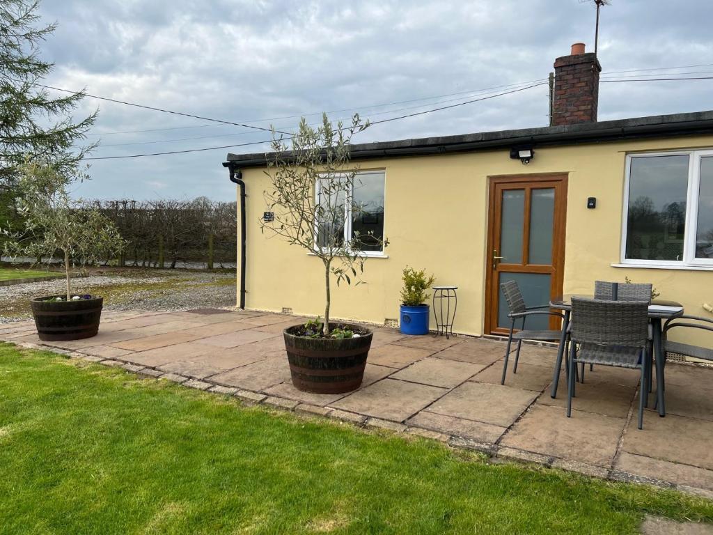 um pátio com uma mesa e cadeiras em frente a uma casa em Yew Tree Bungalow, Onneley, Cheshire em Crewe