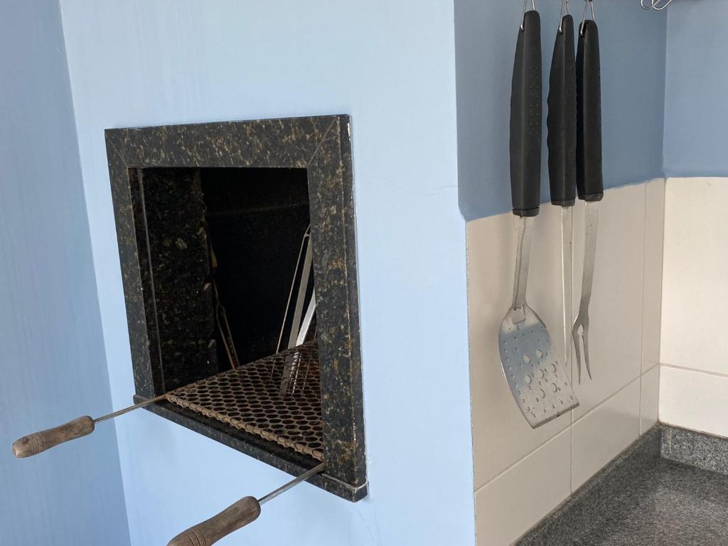 uma cozinha com lareira com facas e utensílios em Casa do Jardim em Curitiba