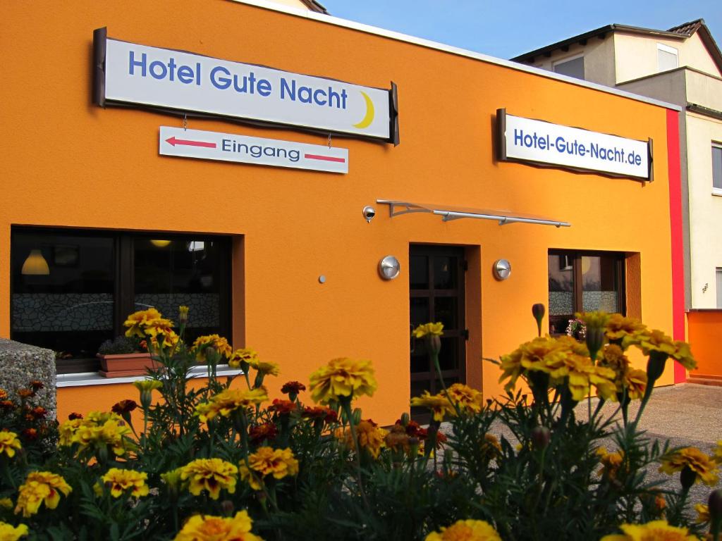 美茵河畔法蘭克福的住宿－Hotel Gute Nacht，一座橙色的建筑,前面有鲜花