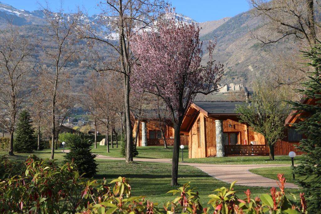 um chalé de madeira com montanhas ao fundo em Lazy Bee Camping Village em Aosta