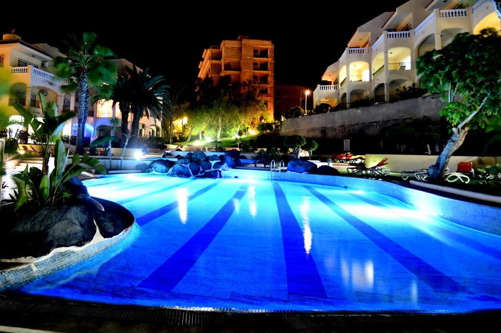 uma grande piscina com iluminação azul à noite em GOLF PARK Resort em San Miguel de Abona