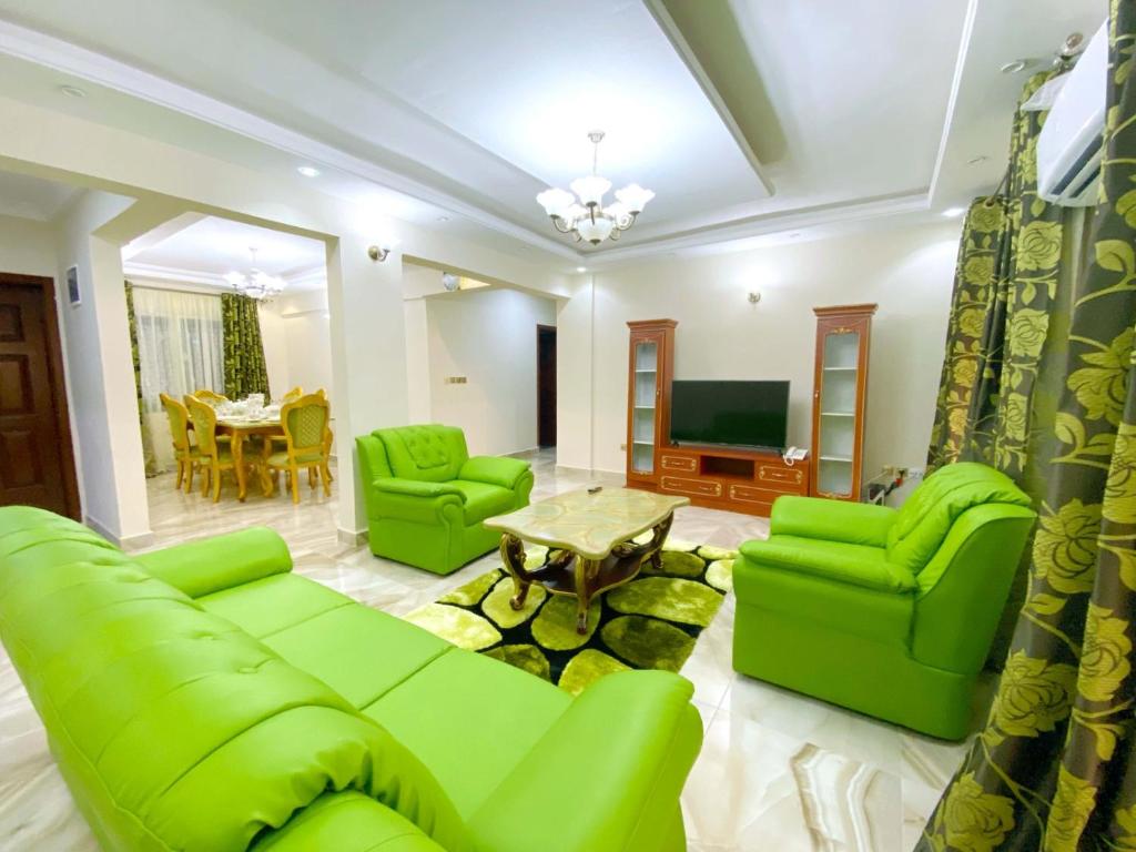 un salon avec un mobilier vert et une télévision dans l'établissement FARLEYVETTE GUEST HOUSE, à Yaoundé