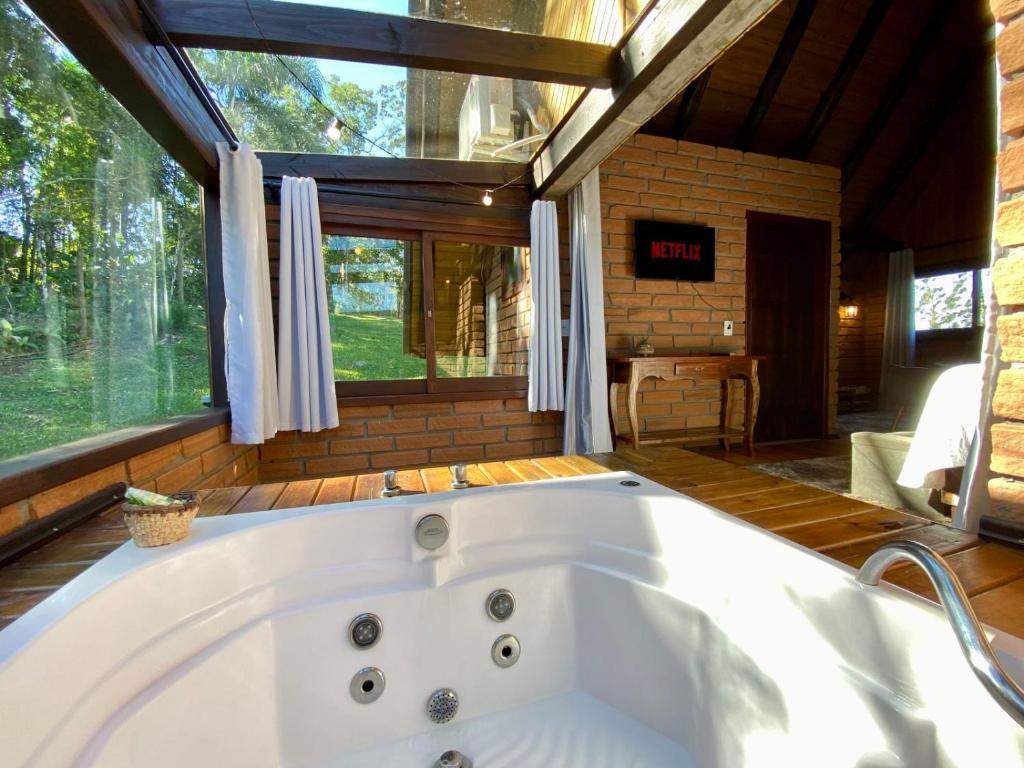 una gran bañera blanca en una habitación con ventana en Maria Rita dos Canyons, en Praia Grande