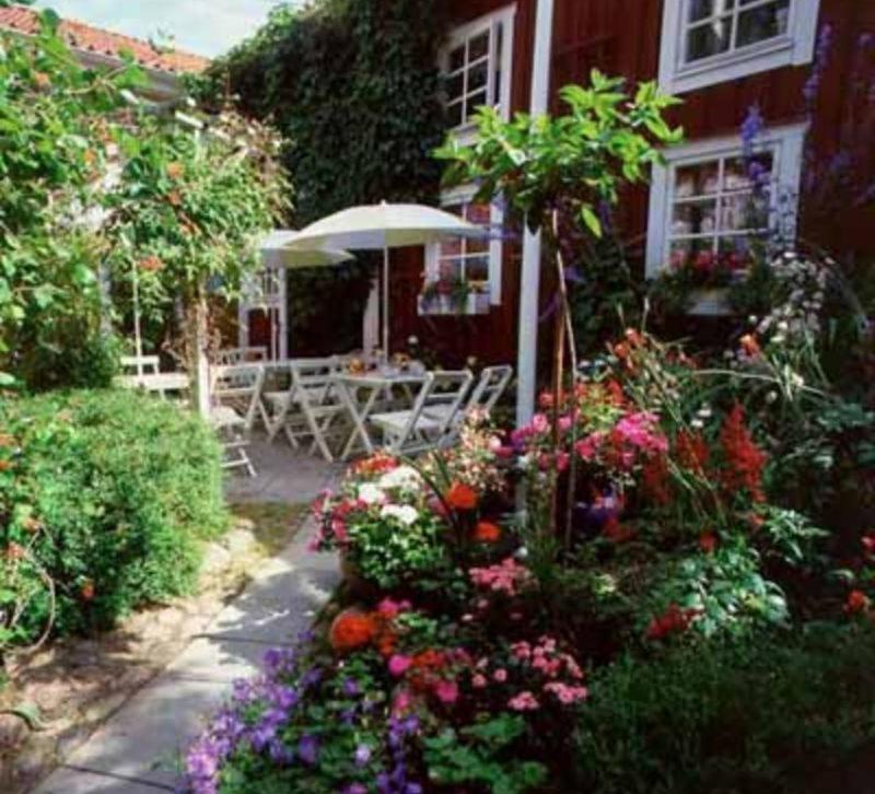 un jardin fleuri devant une maison dans l'établissement Garvaregården Hotel , B&B och Café, à Askersund