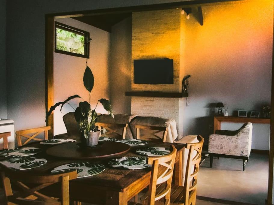 comedor con mesa, sillas y TV en Sitio Por do Sol - Hospedagem, en Delfim Moreira