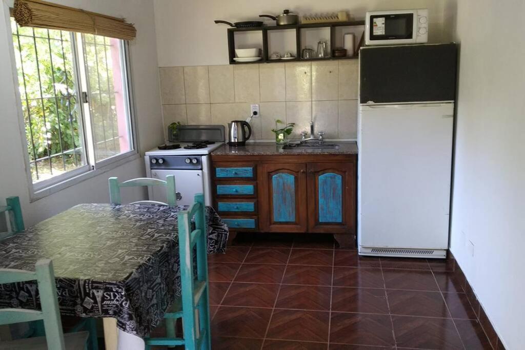 uma cozinha com uma mesa e um frigorífico branco em Casa del bosque em Benavídez