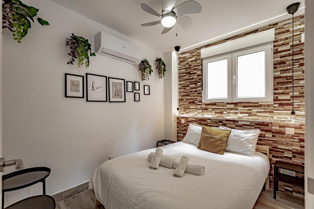 a bedroom with a white bed with a brick wall at Apartamentos Santiago Cordero in Madrid