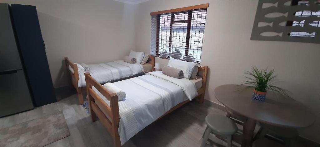 1 dormitorio con 2 camas, mesa y ventana en 22 on Port Natal Hartenbos, en Hartenbos