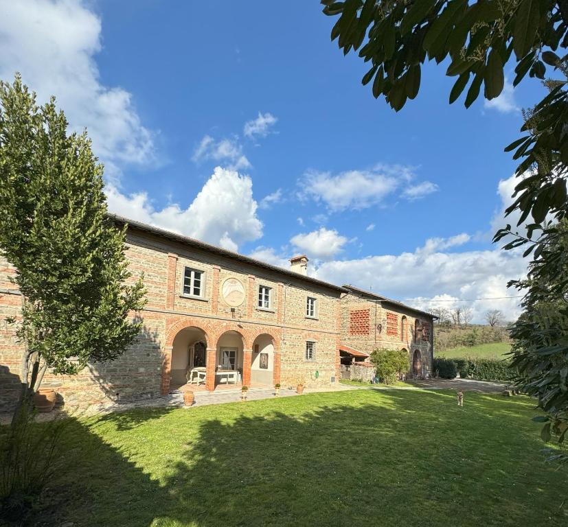 einen Außenblick auf ein großes Backsteingebäude mit einem Hof in der Unterkunft Casale San Giorgio in Luco di Mugello