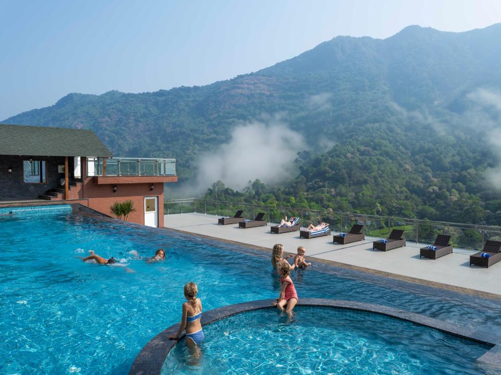 a group of children playing in a swimming pool at The Grand Cliff Resort Munnar in Viripara